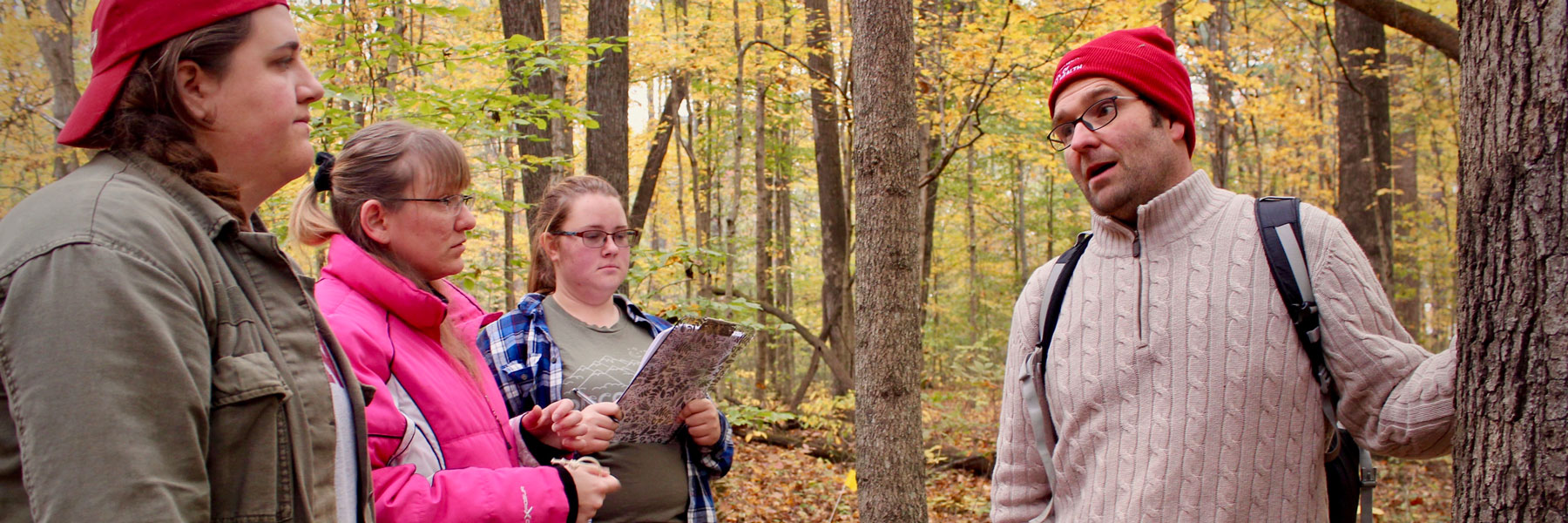 IU professor talking with students in an outdoor forest setting. 